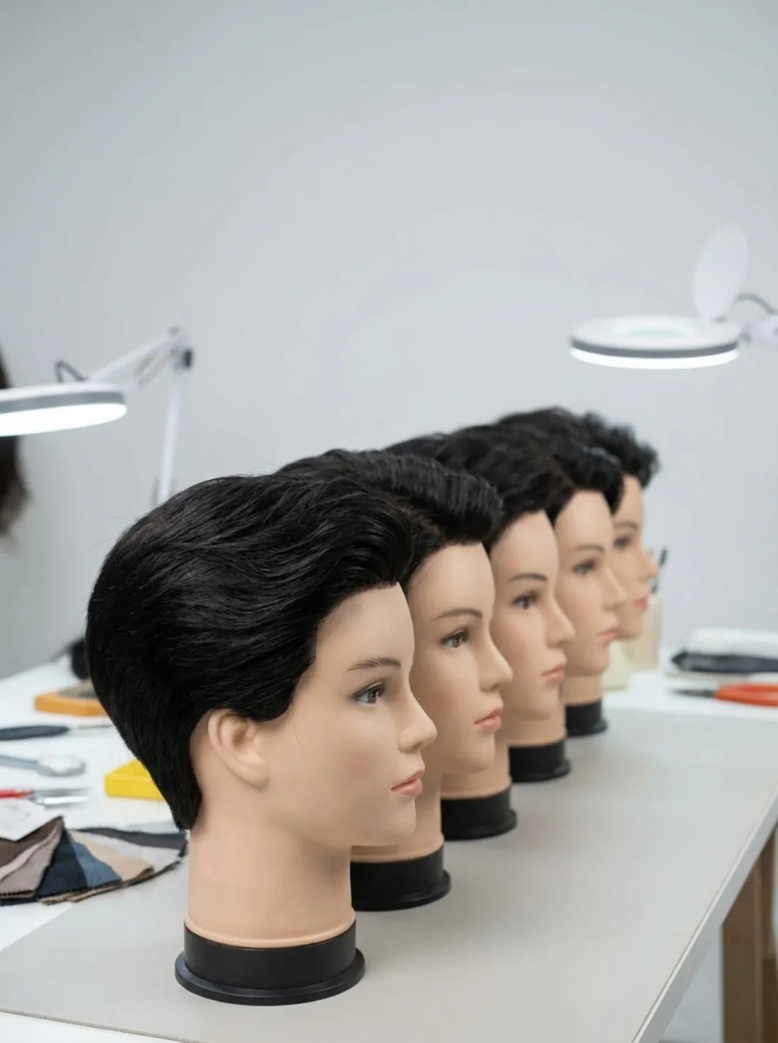 Finished toupees on mannequin heads awaiting inspection