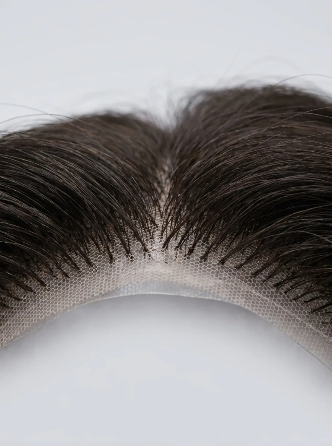 Macro detail of hand-knotted hair strands on lace base